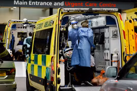 Nhân viên y tế chuyển bệnh nhân COVID-19 tới bệnh viện tại London, Anh. (Ảnh: AFP/TTXVN)