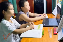 Nhiều trường hợp 2 học sinh phải học chung trên một thiết bị. (Ảnh: TTXVN phát)
