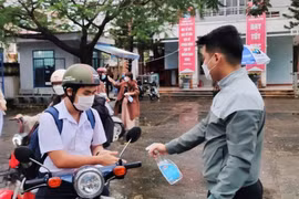 Học sinh trường THPT Hoàng Hoa Thám xịt sát khuẩn tay tại cổng trường. (Ảnh: Văn Dũng/TTXVN)