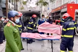 Lực lượng chức năng đưa những nạn nhân của vụ cháy ra ngoài. (Ảnh: TTXVN phát)