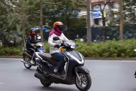 Người dân khi ra đường nên mặc ấm, đeo khẩu trang và mang theo áo mưa đề phòng những cơn mưa. (Ảnh: Tuấn Đức/TTXVN)