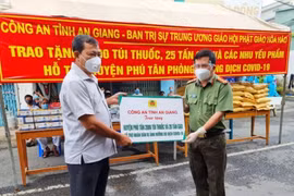 Đại tá Đinh Văn Nơi, Giám đốc Công an tỉnh trao bảng hỗ trợ quà cho lãnh đạo huyện Phú Tân, An Giang. (Ảnh: Thanh Sang/TTXVN)