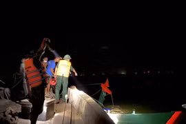 Lực lượng chức năng cùng người dân kéo tàu cá gặp nạn vào bờ. (Nguồn: plo.vn)