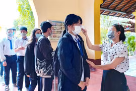 Thí sinh được đo thân nhiệt trước khi vào điểm thi. (Ảnh: Thu Hiền/TTXVN)