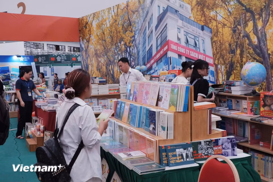 Các em nhỏ và phụ huynh thích thú tham quan, đọc thử và khám phá bộ sách được trưng bày tại gian của Nhà xuất bản Giáo dục Việt Nam. (Ảnh: Phương Trang/Vietnam+)