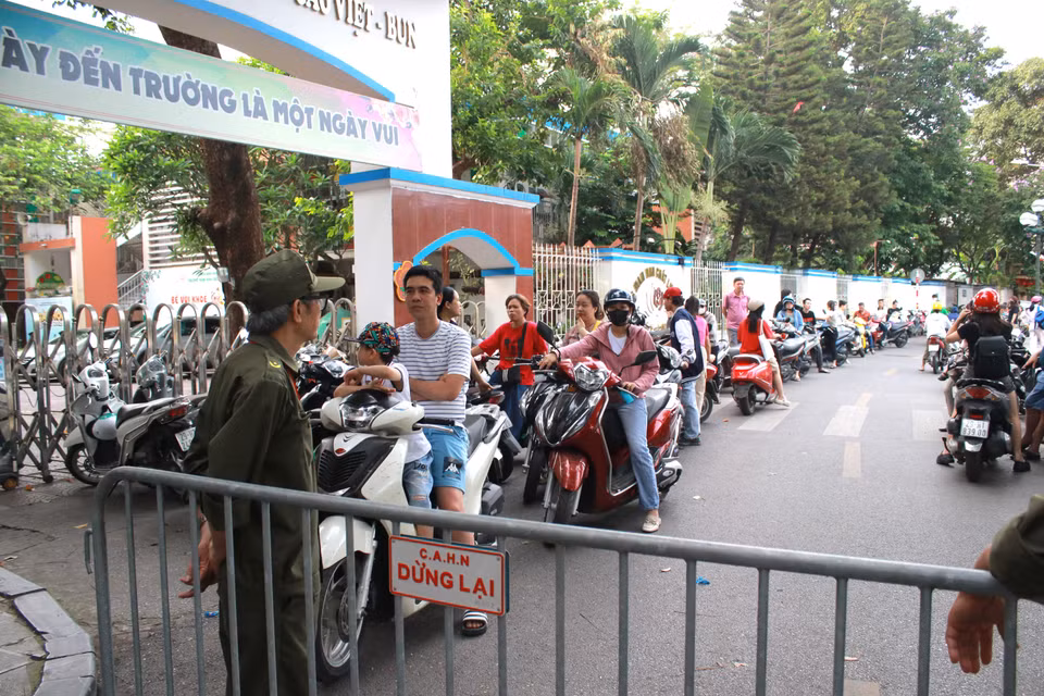 Phần lớn phụ huynh "ứng trực" đến 8 giờ để đảm bảo hỗ trợ kịp thời nếu con quên đồ dùng và chỉ yên tâm khi con bắt đầu làm bài. (Ảnh: Minh Anh/Vietnam+)