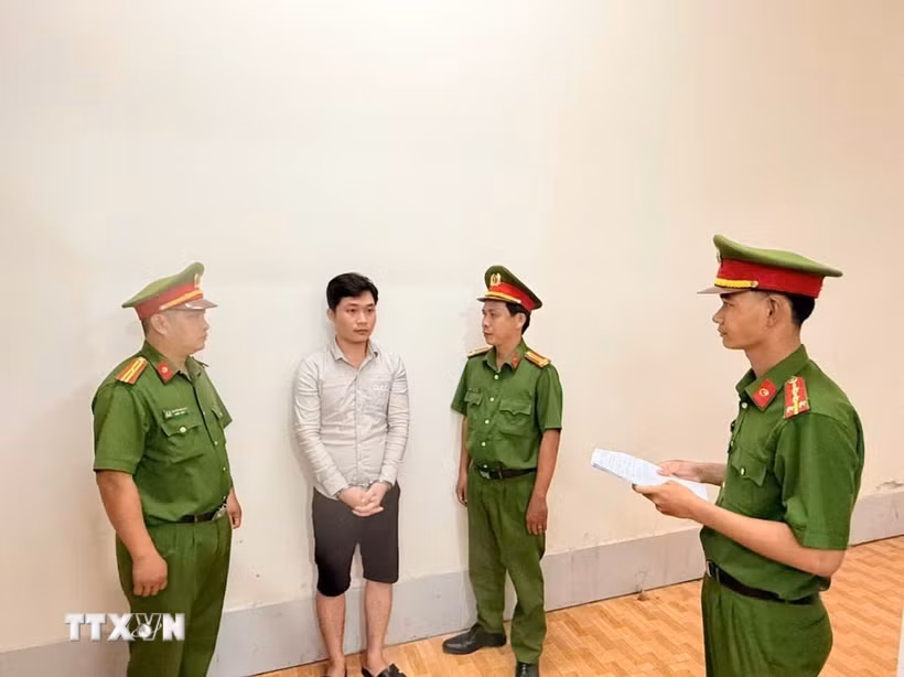 Điều tra viên thi hành lệnh bắt bị can để tạm giam đối với Huỳnh Thanh Huy. (Ảnh: TTXVN phát)