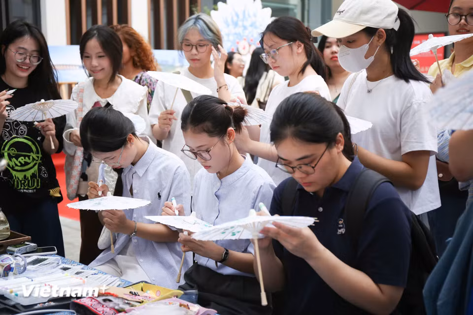 Chương trình gồm nhiều hoạt động như thưởng trà, tô màu “Thỏ gia,” trải nghiệm in rập “Phúc vận,” làm hoa nhung Kinh kịch, làm dấu trang thổ cẩm Choang, làm phụ kiện tóc bằng thổ cẩm Choang, vẽ tay trên ô giấy dầu, trải nghiệm đan tre, cắt giấy là các Di sản văn hóa phi vật thể của địa phương. (Ảnh: Trịnh Ngọc/Vietnam+)