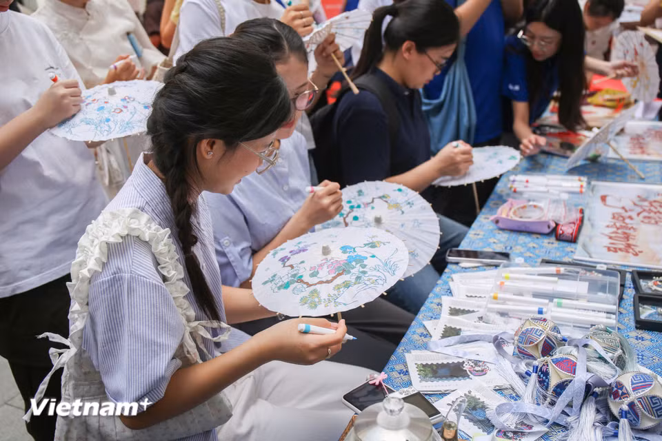 Các bạn trẻ trải nghiệm tô màu trên ô giấy. (Ảnh: Trịnh Ngọc/Vietnam+)