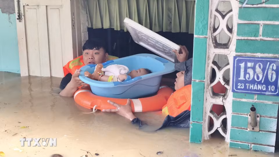 Lực lượng chức năng hỗ trợ đưa trẻ em ra khỏi căn nhà bị ngập sâu ở phường Tây Nha Trang (Khánh Hòa). (Ảnh: Nguyễn Thành/TTXVN)