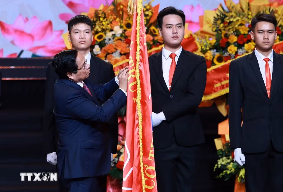 Thủ tướng Phạm Minh Chính gắn Huân chương Hồ Chí Minh lên Cờ truyền thống của Đài Tiếng nói Việt Nam. (Ảnh: Dương Giang/TTXVN)